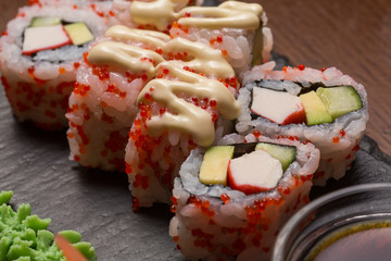 Uramaki sushi rolls with shrimp, cucumber topped with sauce and  caviar