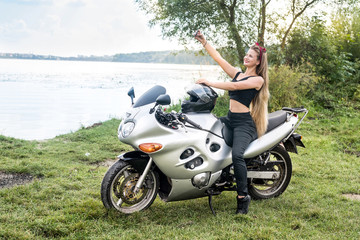 Fototapeta na wymiar Young woman making selfie on motorbike outdoors