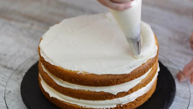 Pastry chef in the kitchen decorating a cake. Making cake with pineapple filling.