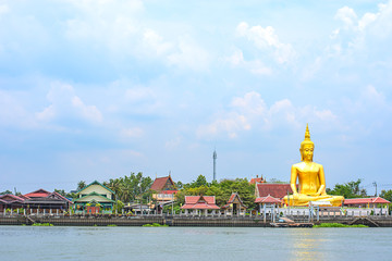 Obraz premium Big Buddha golden and the house behind Chao Phraya River. Background sky and clouds at Wat Bang Chak in Nonthaburi , Thailand.