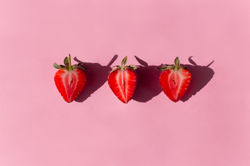 pink background with three fresh Strawberry halves, the shadows