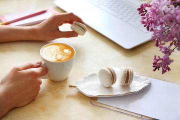 Top view shot of woman typing on white laptop computer, concrete textured table background. Feminine workspace with flowers bouquet. Close up, copy space.