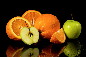 Apples and oranges fruits with drops and splashes of water on a black background