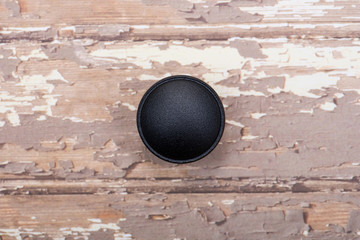 Classic Black Round Cabinet Knob isolated on wooden background.