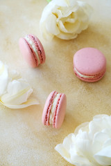Feminine composition with traditional french macarons sweets and tender bicolor tulip flowers on yellow concrete textured background. Top view, close up, copy space.