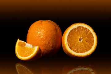 Oranges fruit with drops and splashes of water on a black background