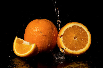 Fototapeta na wymiar Oranges fruit with drops and splashes of water on a black background