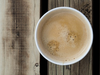 Cup of coffee to go on the wooden table. Street coffee, top view.