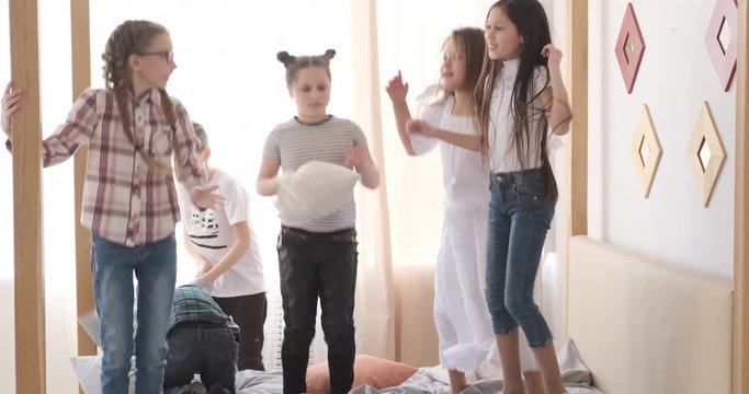 Children jumping and having pillow fight on bed