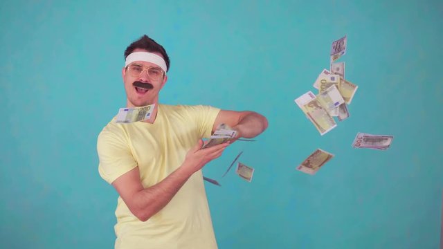 a cheerful man with a mustache looks at the camera and throws a pack of money