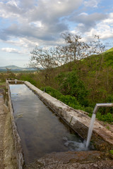 Source of spring water in the forest, small mountain village in the background.