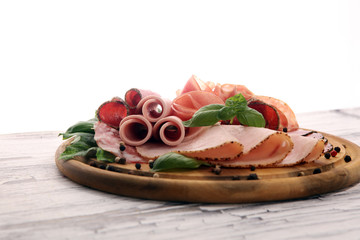 Food tray with delicious salami, pieces of sliced ham, sausages,salad and vegetable. Meat platter with selection