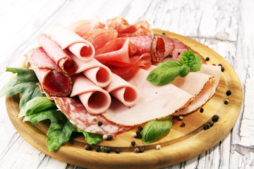 Food tray with delicious salami, pieces of sliced ham, sausages,salad and vegetable. Meat platter with selection