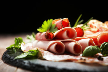 Food tray with delicious salami, pieces of sliced ham, sausages,salad and vegetable. Meat platter with selection