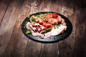 Food tray with delicious salami, pieces of sliced ham, sausages,salad and vegetable. Meat platter with selection