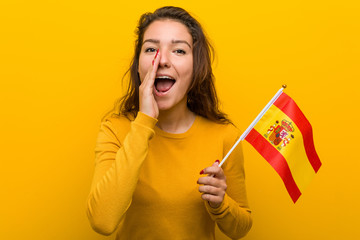 Young european woman holding a spanish flag shouting excited to front.