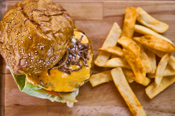 Cheeseburger with french fries on the wooden table