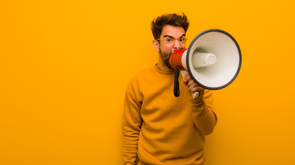 Young man holding a megaphone whispering gossip undertone