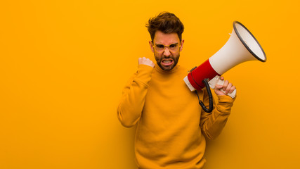 Young man holding a megaphone screaming very angry and aggressive