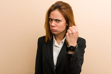 Young caucasian business woman showing fist to camera, aggressive facial expression.