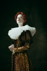 I make decisions. Medieval redhead young woman in golden vintage clothing as a duchess standing...