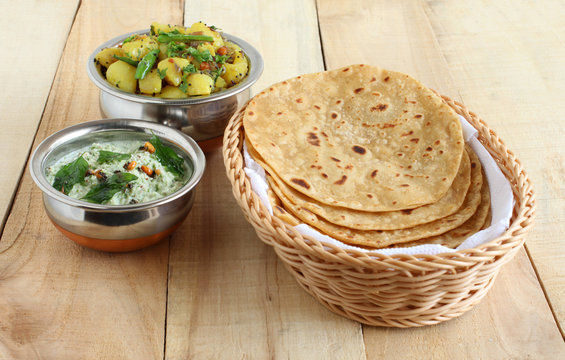 Chapati or Indian flat bread, which is a traditional and popular vegetarian breakfast or lunch item, with potato and onion curry and coconut chutney as side dishes.