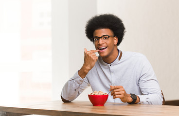 Fototapeta na wymiar Young black man having a breakfast smiles, pointing mouth
