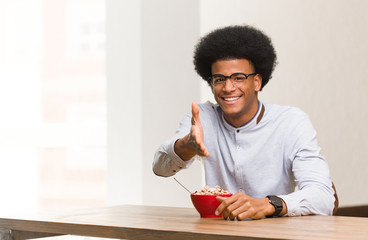 Fototapeta na wymiar Young black man having a breakfast reaching out to greet someone