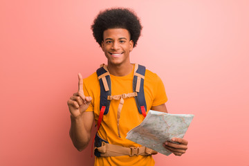 Young african american explorer man holding a map showing number one
