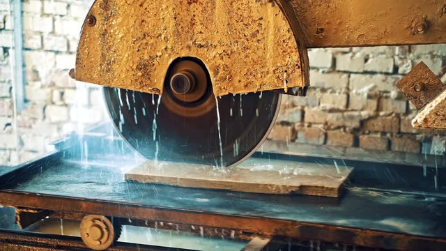 Circle wheel of electric machine for cutting stone slab. CNC manufactoring machine of sawing stone. Process of cutting slab with water. Close-up.