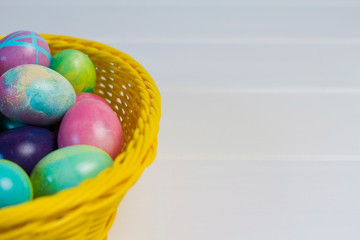 Easter eggs in a basket on a wooden white background. basket of eggs