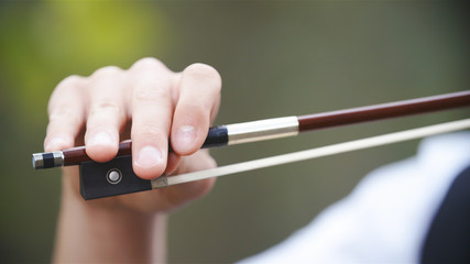 Person hold violin bow close-up