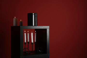 Mortuary urn with burning candles on color background