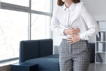 Young woman suffering from abdominal pain in office