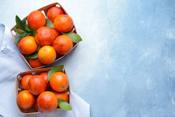 Boxes with fresh blood oranges on color background