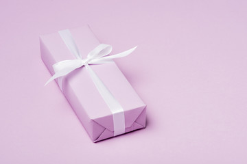 gift box with white ribbon on purple surface