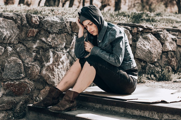 Poor homeless woman sitting on stairs outdoors