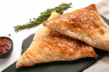 Slate board with delicious samosas on light background, closeup