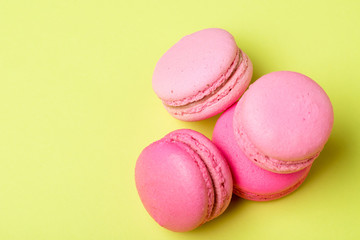 tasty pink macarons with filling on yellow surface