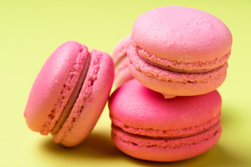 tasty pink macarons with filling on yellow surface