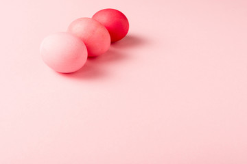 three colorful painted easter eggs on pink surface