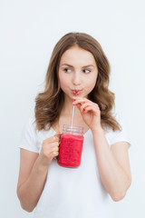 Beautiful happy young girl drinks organic berry, fruit smoothie on a white background.