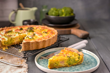 Traditional broccoli pie with salmon and cheese. Food from healthy and healthy foods. Lunch. A piece of cake in the frame on a plate. Dark photo.