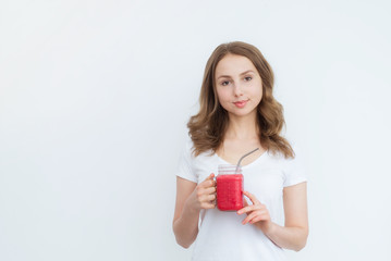 Berry fruit red smoothie in the hands of a young attractive girl on a white background.