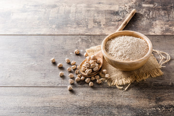 chickpea flour in wooden bowl on wooden table. Copyspace