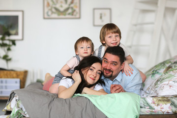 Happy family with two young sons on bed in bedroom