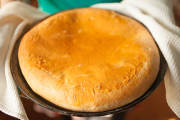 Female hands holding a pie.