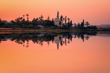 Fototapeta na wymiar The ancient mosque Hala Sultan Tekkes on the shore of the salt lake in Larnaca, Cyprus during the sunset
