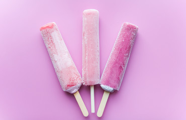Bright fruit ice cream on a stick on a pink background. Frozen fruit ice. Summer mood. Cooling dessert in hot weather. Favorite delicacy for children. Homemade raspberry, strawberry, watermelon ice