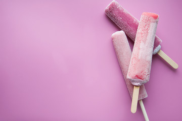 Bright fruit ice cream on a stick on a pink background. Frozen fruit ice. Summer mood. Cooling dessert in hot weather. Favorite delicacy for children. Homemade raspberry, strawberry, watermelon ice